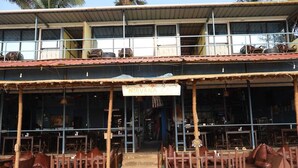 A two-story building with a sign reading "NIRVANA CAFE". - Nirvana Beach Cottages (Canacona)