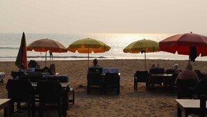 Een restaurant aan het strand met terras en parasols.