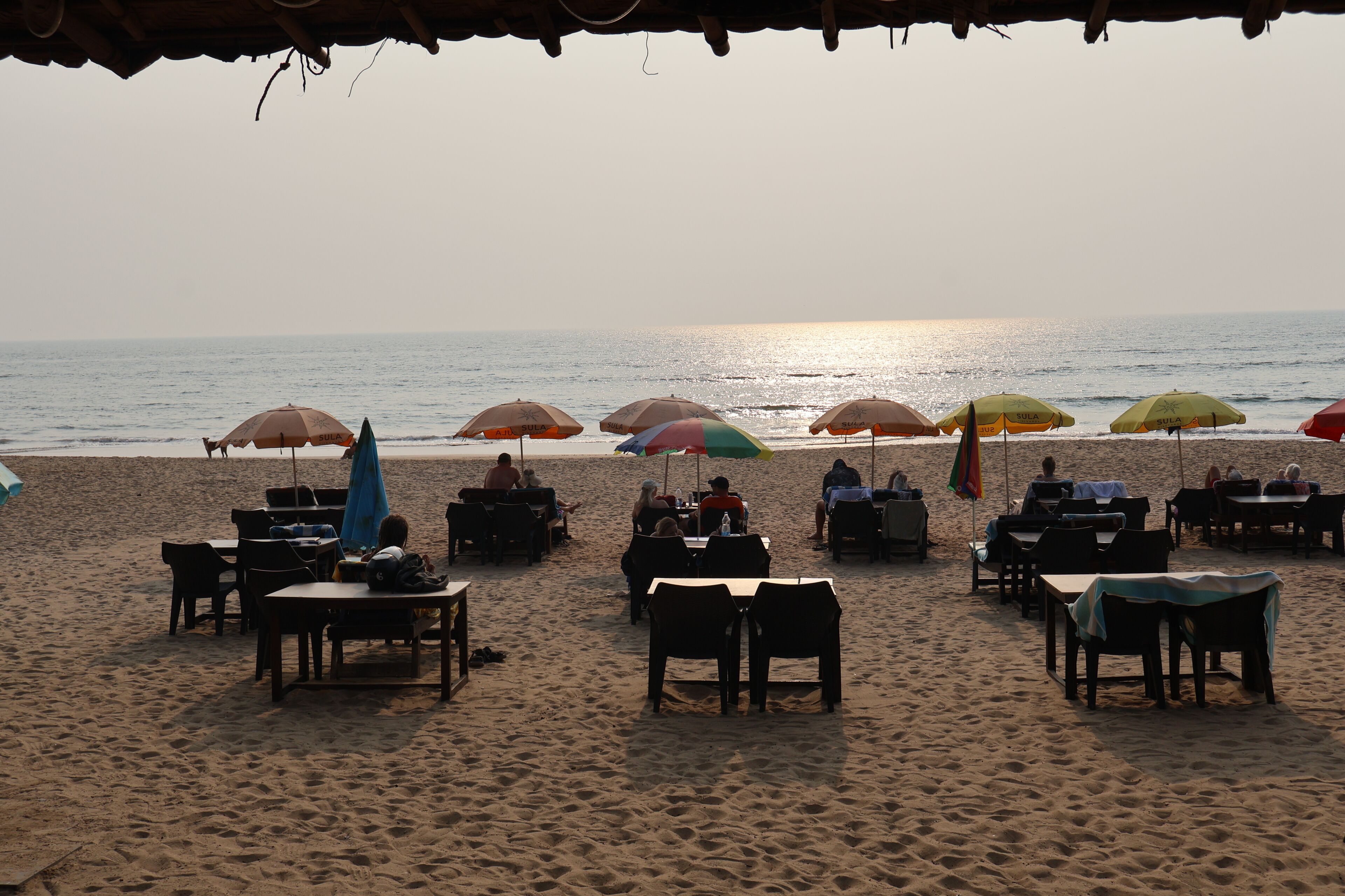 A beachside restaurant with outdoor seating and umbrellas.
