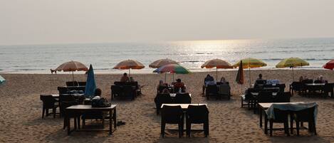 A beachside restaurant with outdoor seating and umbrellas.