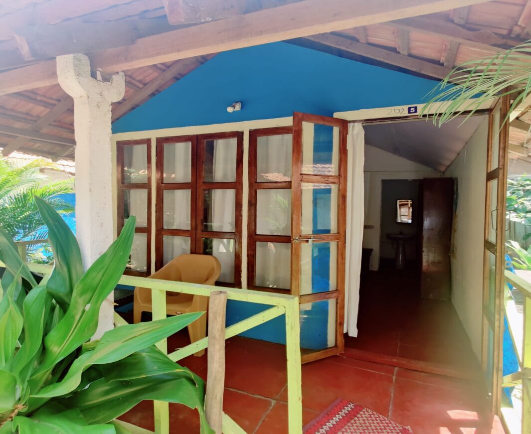 A covered outdoor area with a blue wall, wooden-framed windows, and a yellow railing.