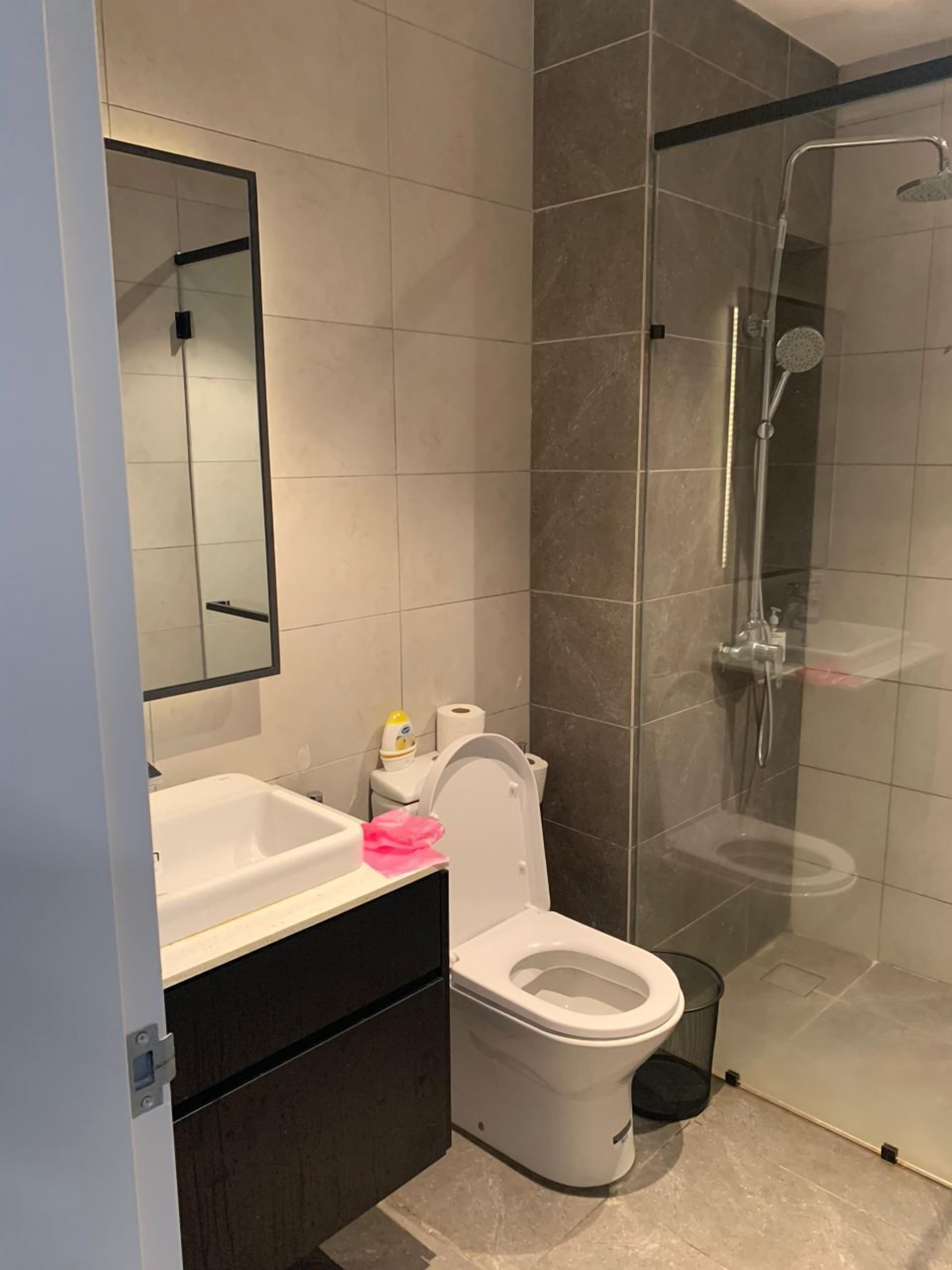 A modern bathroom with a glass-enclosed shower, a white toilet, and a vanity with a mirror.