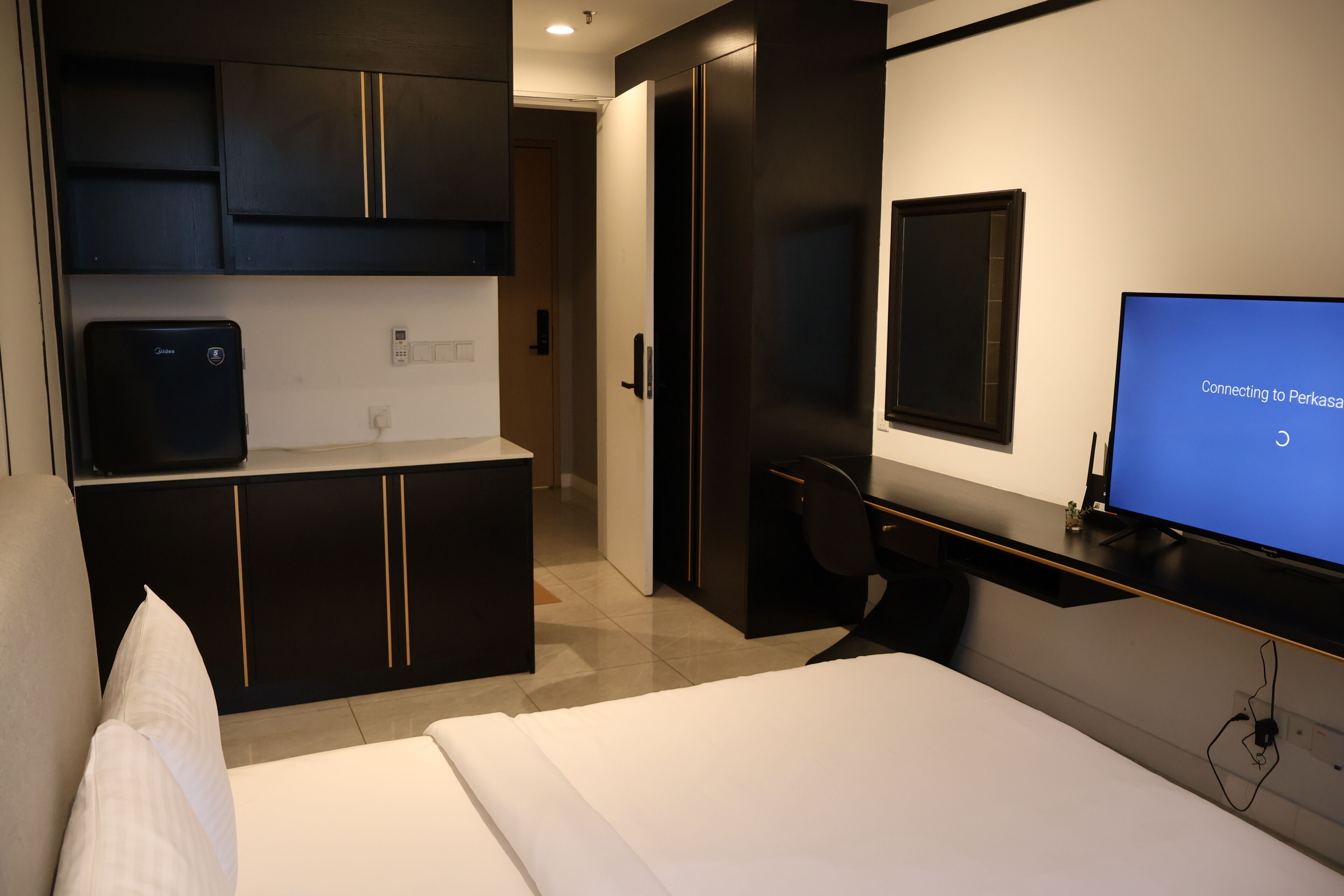 Una habitación de hotel moderna con cama, escritorio, televisión y minibar.