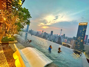 An infinity pool with a city skyline view, surrounded by greenery and modern buildings. - AXON RESIDENCE BY PERKASA IKON (Kuala Lumpur)