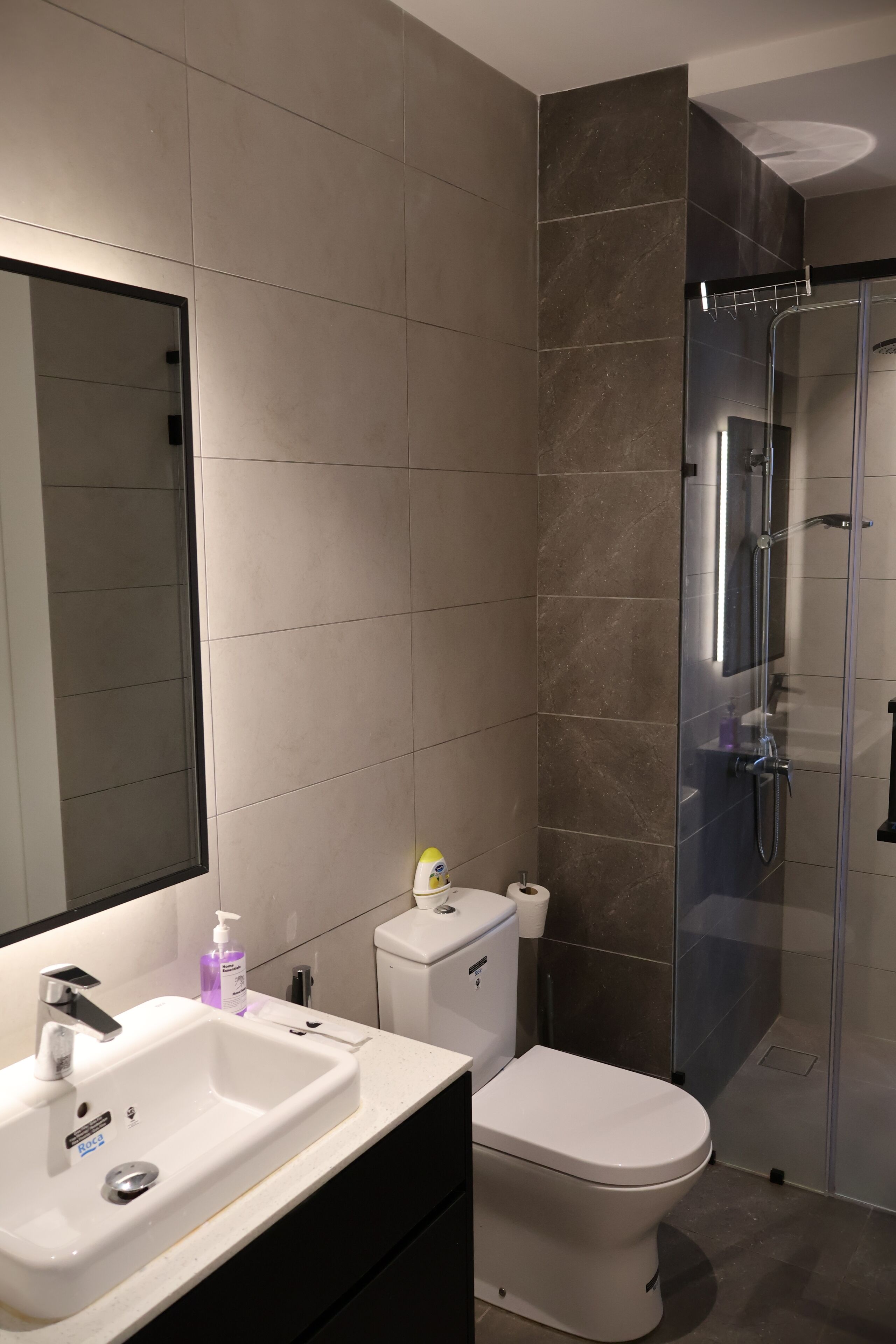Un baño moderno con lavamanos, inodoro y ducha blancos.