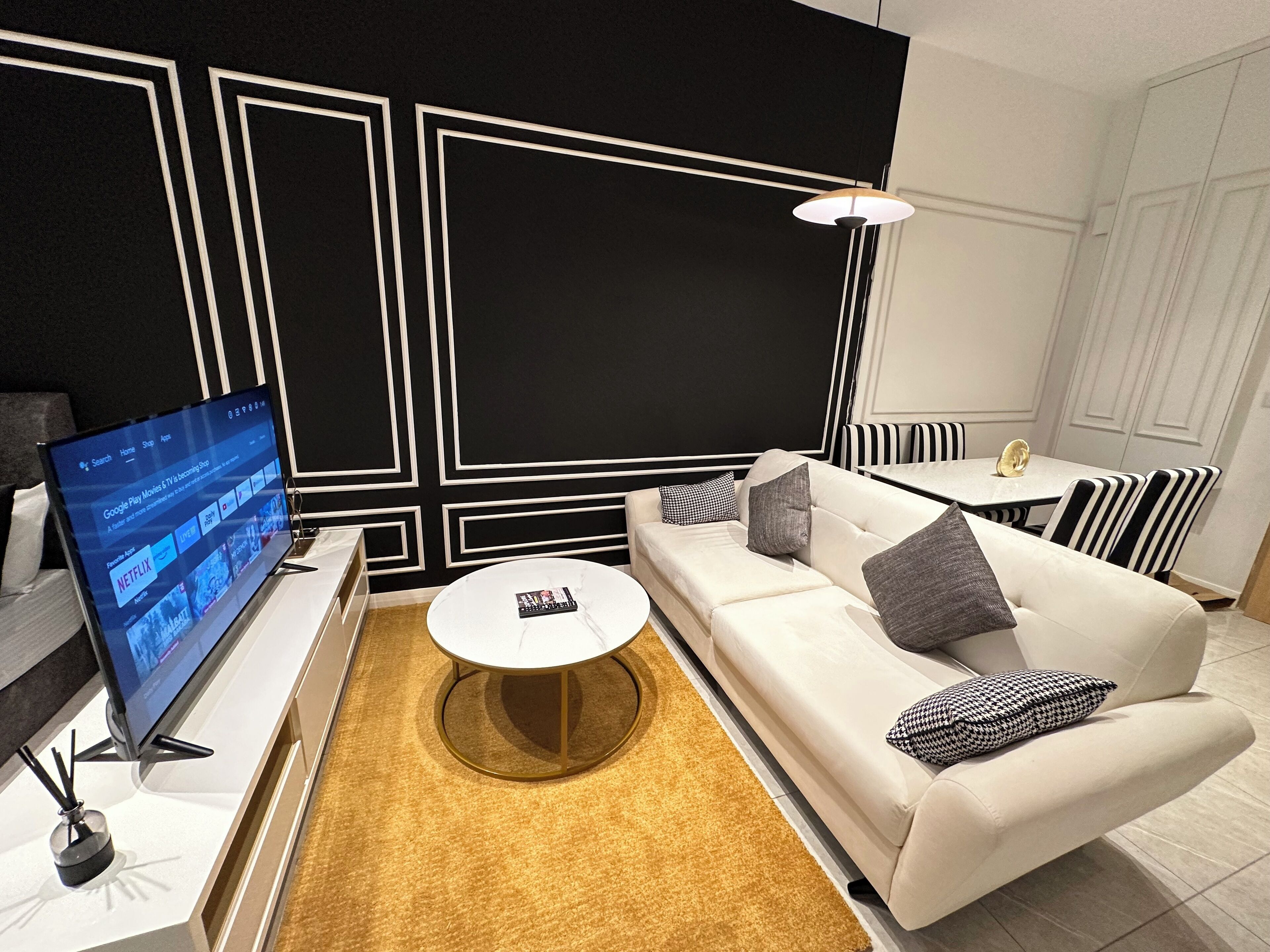 Ein modernes Wohnzimmer mit einem weißen Sofa, einem runden Couchtisch und einem Fernseher, der eine Netflix-Oberfläche zeigt.