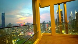 A high-rise building with a view of a cityscape at dusk, featuring illuminated skyscrapers and a clear sky.