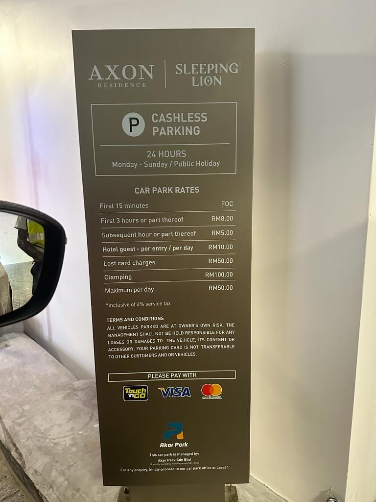 Een parkeersbord voor Axon Residence, Sleeping Lion, dat 24-uurs contactloos parkeren met tarieven voor verschillende tijdsduren aangeeft.