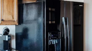 A kitchen with wooden cabinets, a black refrigerator, and a water dispenser.