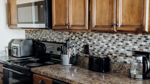 A kitchen with wooden cabinets, a microwave, a toaster, a coffee maker, and a knife block.