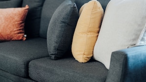 A dark grey sofa with multiple cushions in various colors.