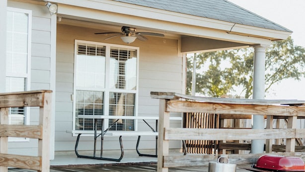 A house with a porch, a grill, and a wooden deck.