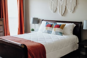 A neatly made bed with a white quilt, a red throw blanket, and colorful pillows. - The space and privacy of a house without giving up convenience. (Prattville)