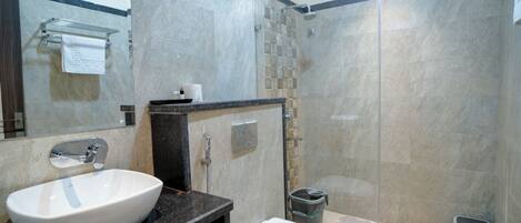 A modern bathroom with a large white sink, a toilet, and a glass-enclosed shower area.
