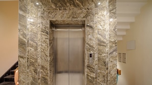 An elevator with a marble wall and a digital control panel. - Omkar International Hotel (VARANASI)