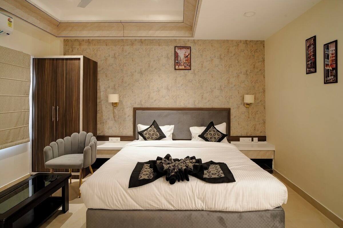 A hotel room with a large bed, a wardrobe, a seating area, and a small table.