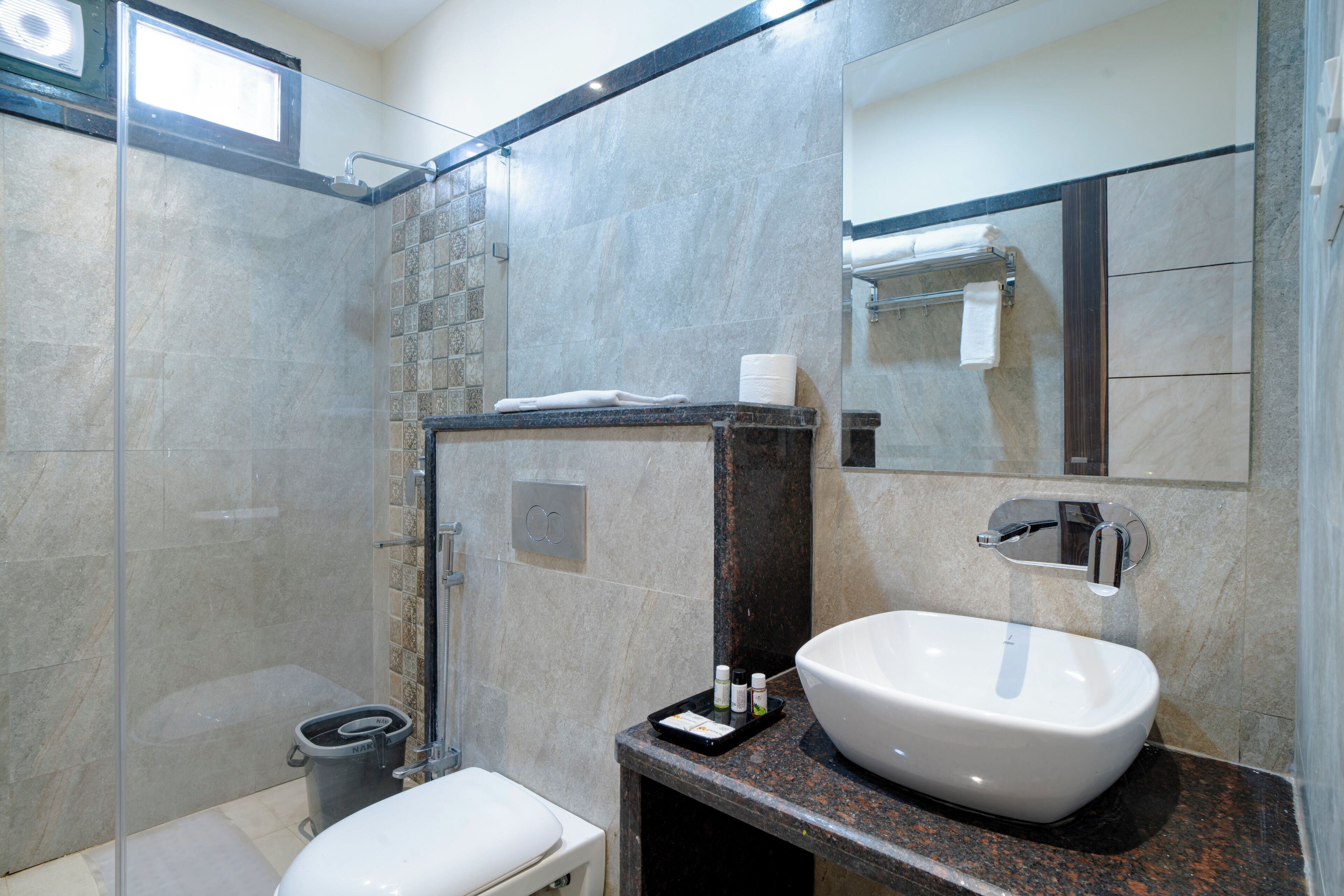 A modern bathroom with a glass-enclosed shower, a white sink, and a mirror above the sink.
