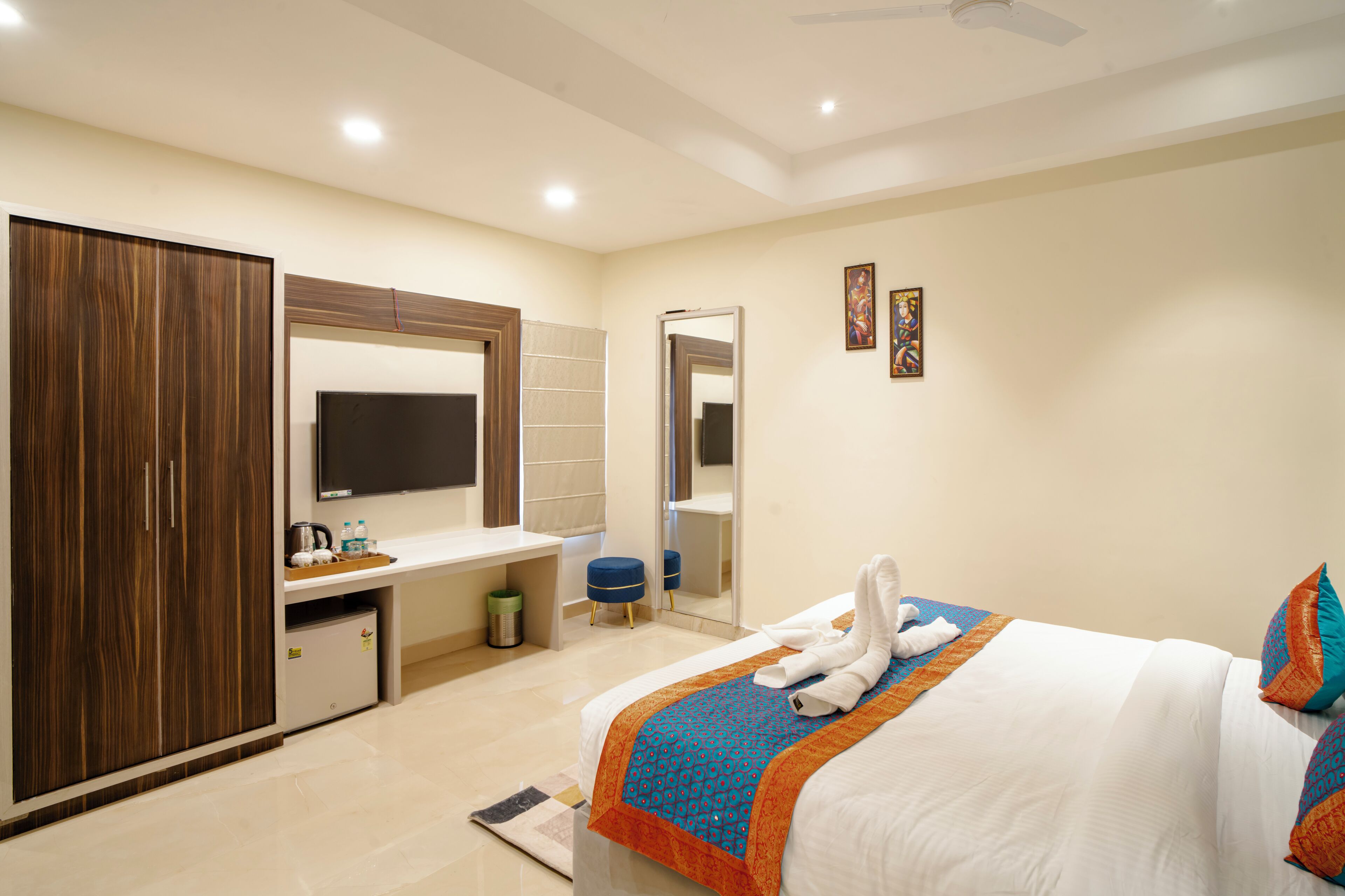 A hotel room with a bed, a wardrobe, a desk with a mirror, and a television.