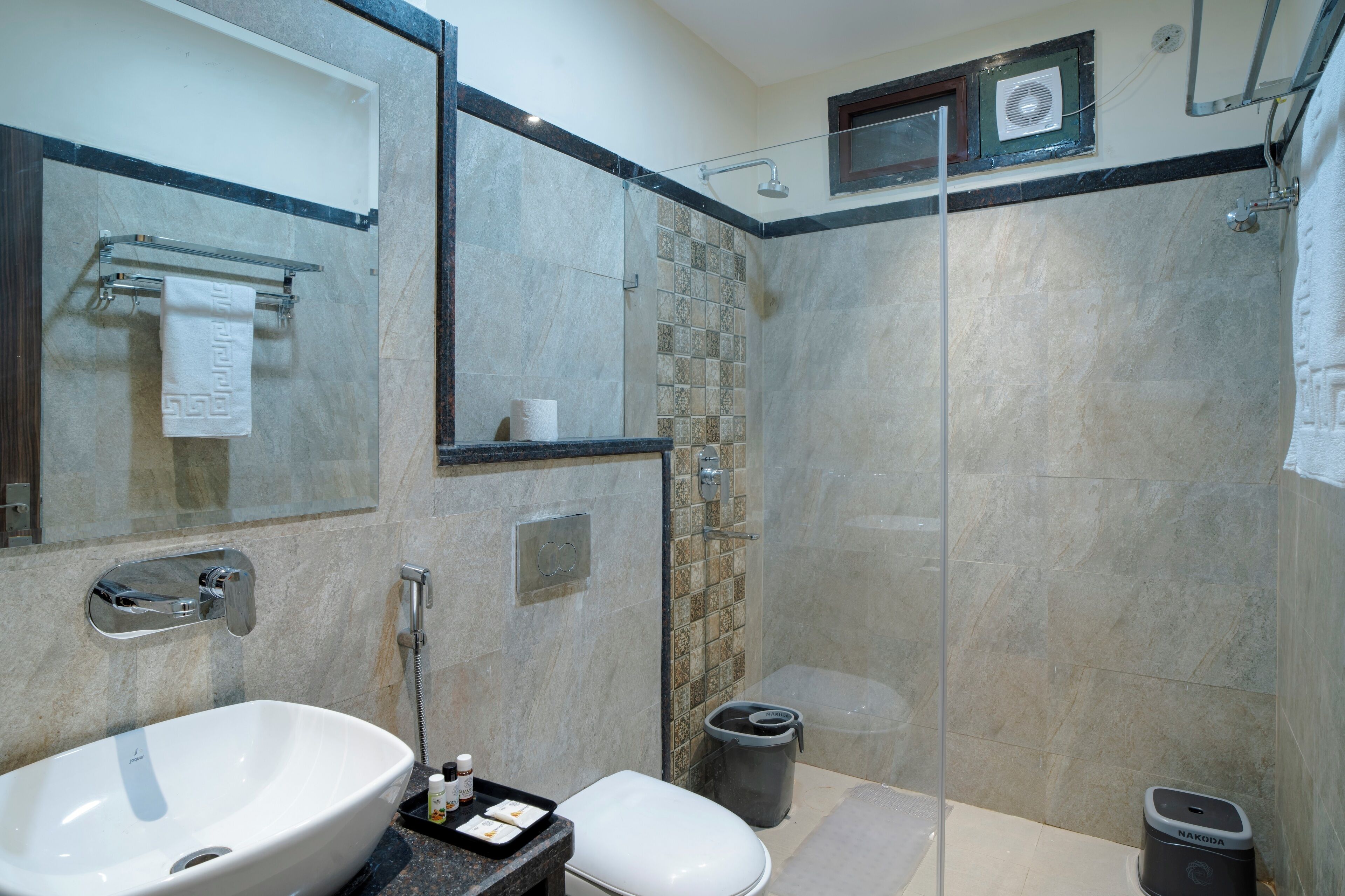A modern bathroom with a large sink, toilet, and glass-enclosed shower.