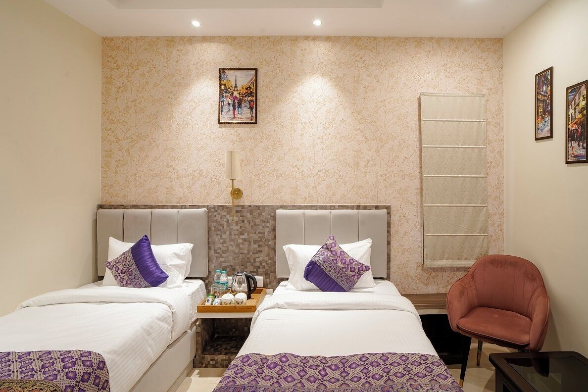 A hotel room with two beds, a nightstand, a chair, and artwork on the walls.