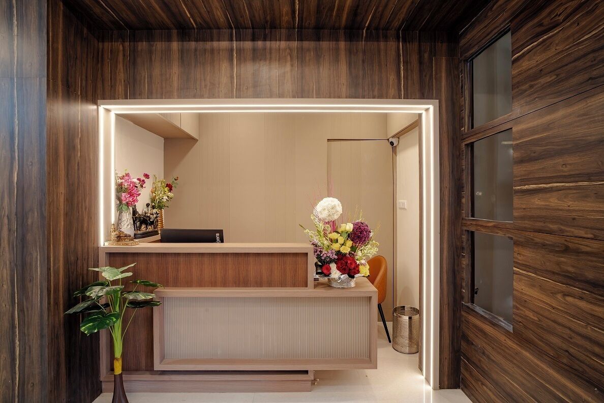 A reception desk with a mirror, a vase of flowers, and a potted plant.