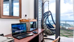 A modern room with a laptop on a desk, a hanging chair, and a view of the sea. - Hammock CoCo-Nut - by ZenBreak (Morne Fortune)