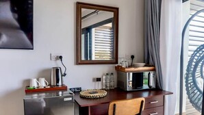 A hotel room with a kitchenette, a desk, a chair, a large mirror, and a view of a spiral staircase. - Hammock CoCo-Nut - by ZenBreak (Morne Fortune)