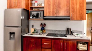 A kitchen with wooden cabinets, a stainless steel refrigerator, a microwave, and a sink.