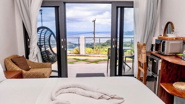 Habitación de hotel con cama, una silla, una mesita y vistas al exterior.