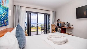 Habitación de hotel con cama, televisión, escritorio y tetera, y vistas al exterior.
