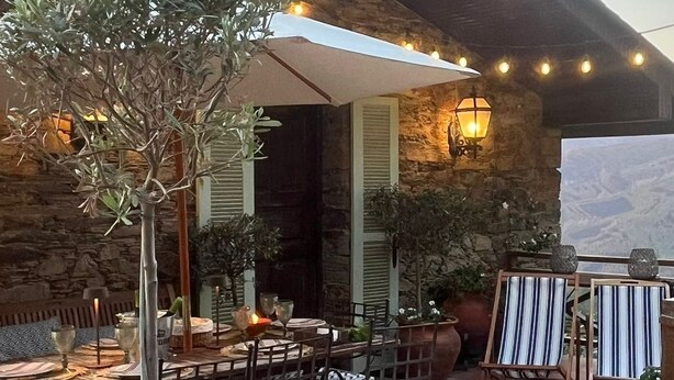 Un patio al aire libre con zona de comedor, muros de piedra y vistas del paisaje.