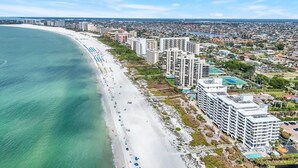 An aerial view of a coastal city with a long beach, high-rise buildings, and a clear sky. - Beachfront 2BR/2BA Somerset condo with pool, WiFi, and heated pool. (Marco Island)