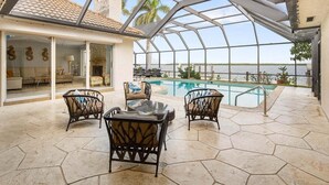 Ein überdachter Außenbereich mit Pool, Sitzgelegenheiten und Blick auf das Wasser.