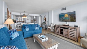 Un salon moderne avec un canapé bleu, une table basse et un téléviseur fixé au mur.