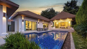 Ein modernes Haus mit Swimmingpool, großen Fenstern und Sitzgelegenheiten im Freien.