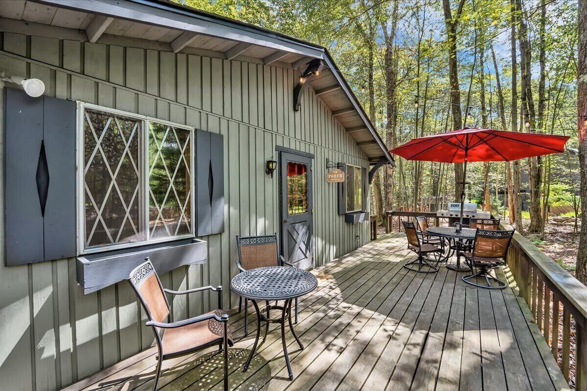 A wooden deck with outdoor furniture and a red umbrella.