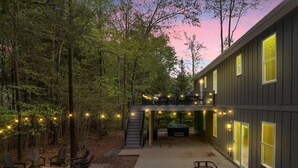 A building with a covered patio, outdoor seating, and a staircase leading to an upper level. - Private Pool Chalet | HotTub | Firepit | Game Room (Blakeslee)