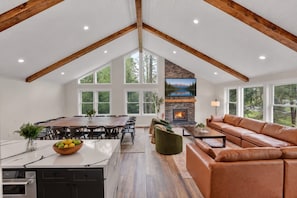 A spacious living area with a fireplace, a large dining table, and a leather sofa.