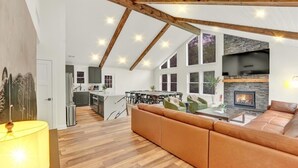 A spacious living area with a high ceiling, wooden beams, a fireplace, and a dining area. - Private Pool Chalet | HotTub | Firepit | Game Room (Blakeslee)