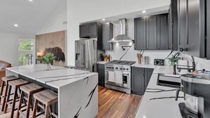 A modern kitchen with a central island, stainless steel appliances, and a large window. - Private Pool Chalet | HotTub | Firepit | Game Room (Blakeslee)