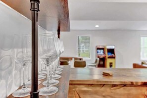 A bar area with a row of empty wine glasses and a wooden table.