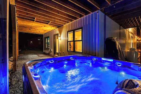 A hot tub in a covered outdoor area with wooden beams and metal walls.