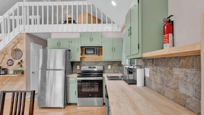 A compact kitchen with a refrigerator, microwave, oven, and a small dining area with a table and chairs.