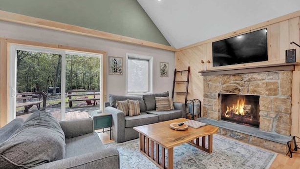 A living room with a stone fireplace, a grey sofa, and a wooden coffee table.
