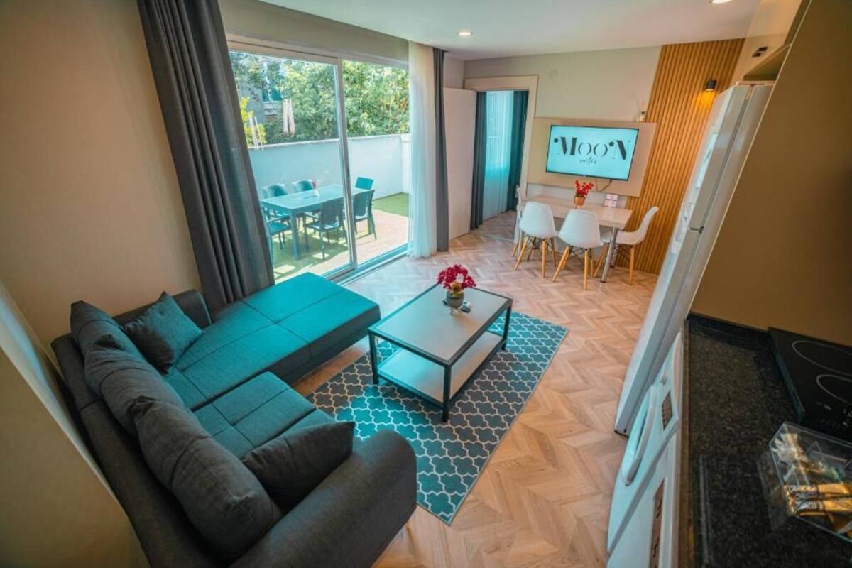 A modern living room with a sofa, coffee table, and a dining area with chairs and a table.