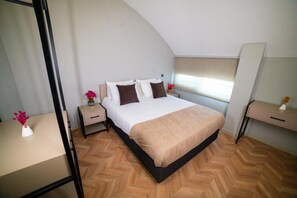 A bedroom with a bed, nightstands, a desk, and a window. - Moon Suites (Antalya)