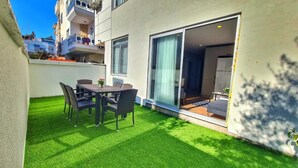 A modern apartment with a balcony, a dining area with a table and chairs, and a sliding glass door leading to a living space. - Moon Suites (Antalya)
