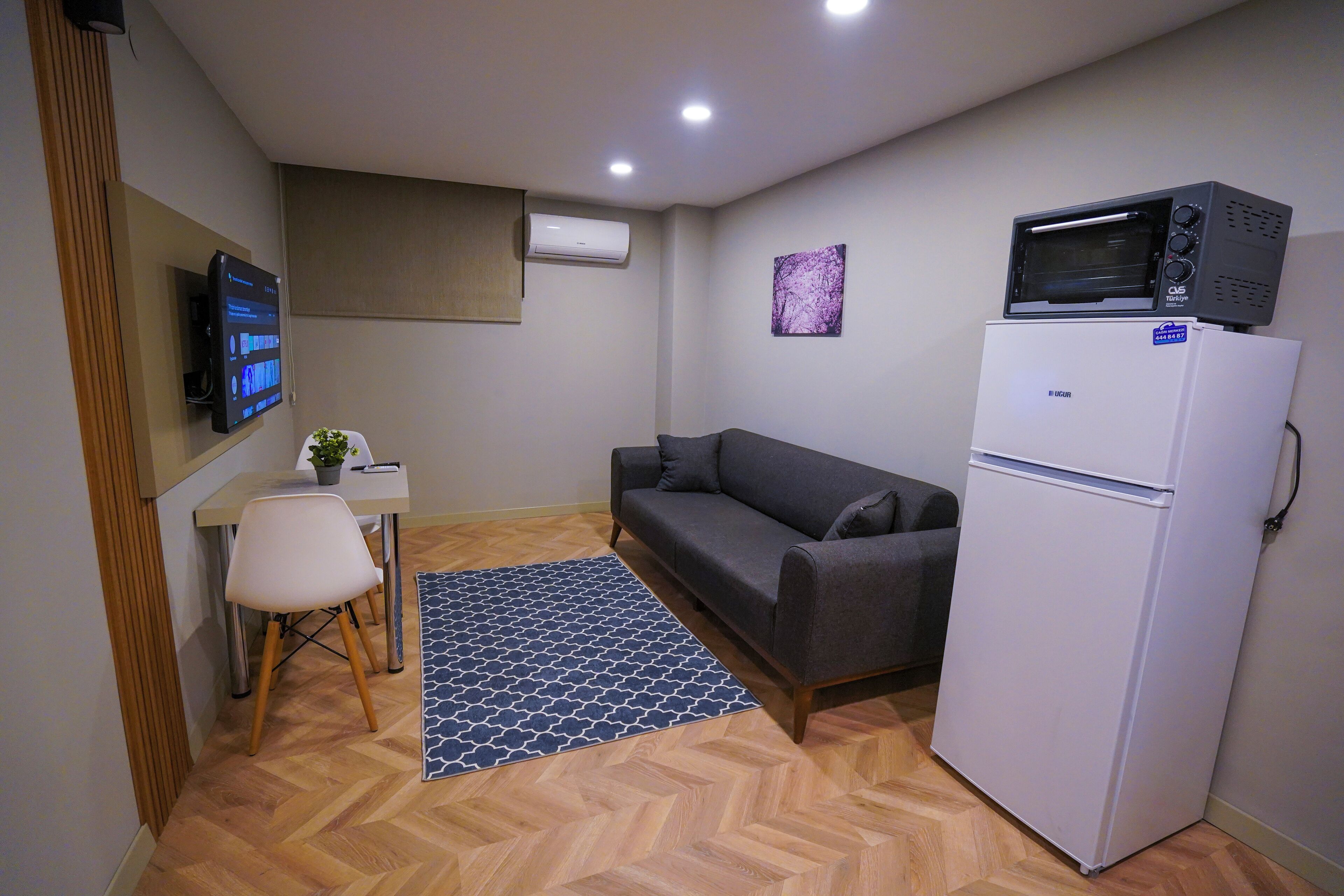 Un espacio habitable compacto con sofá, una mesita con silla, microondas y refrigerador.