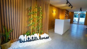A reception area with a wooden wall, a reception desk, and a sign that reads "MOON". - Moon Suites (Antalya)