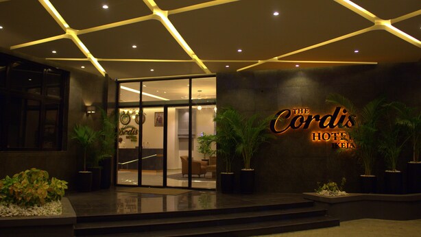The exterior of The Cordis Hotel with a modern entrance, glass doors, and potted plants. - The Cordis Hotel Ikeja (Lagos)